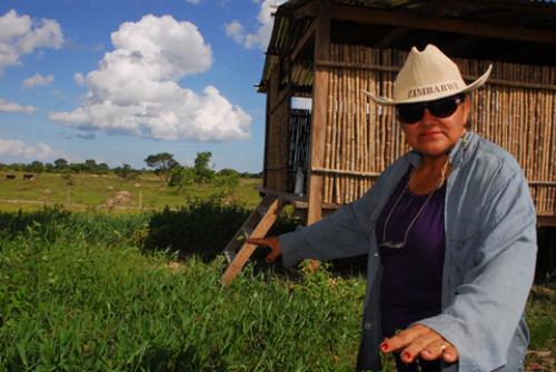 Dora Domínguez shows IPS the forage grown on the artificial hill and the feed storage shed, behind her.: This is an example of an artificial 'island' created to protect cattle and feed from annual floods in Bolivia Photograph by Franz Chávez/IPS